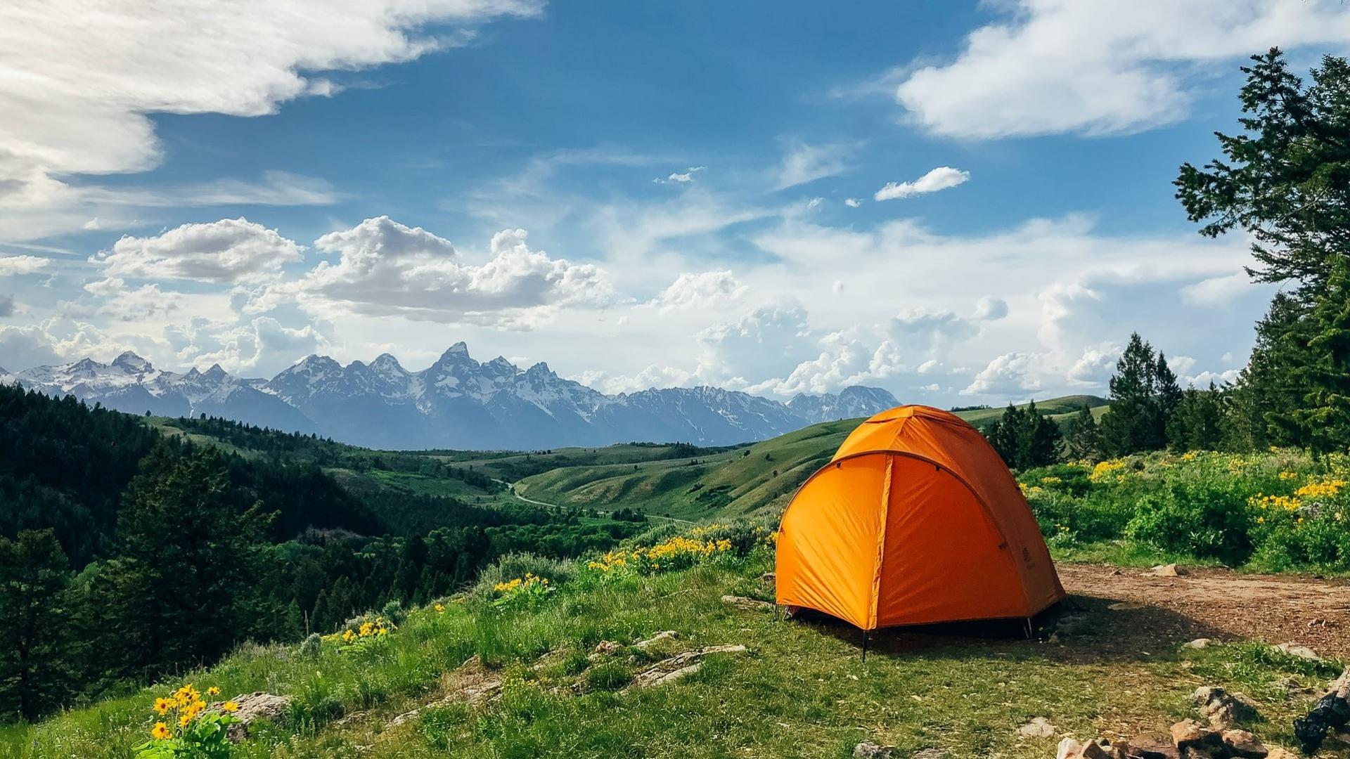 Yellow tent among beautiful mountains and grass