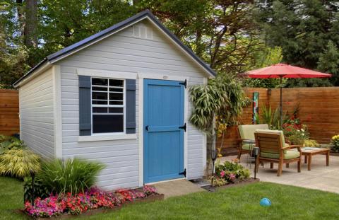 White garden shed with bright blue door in a stylish backyard